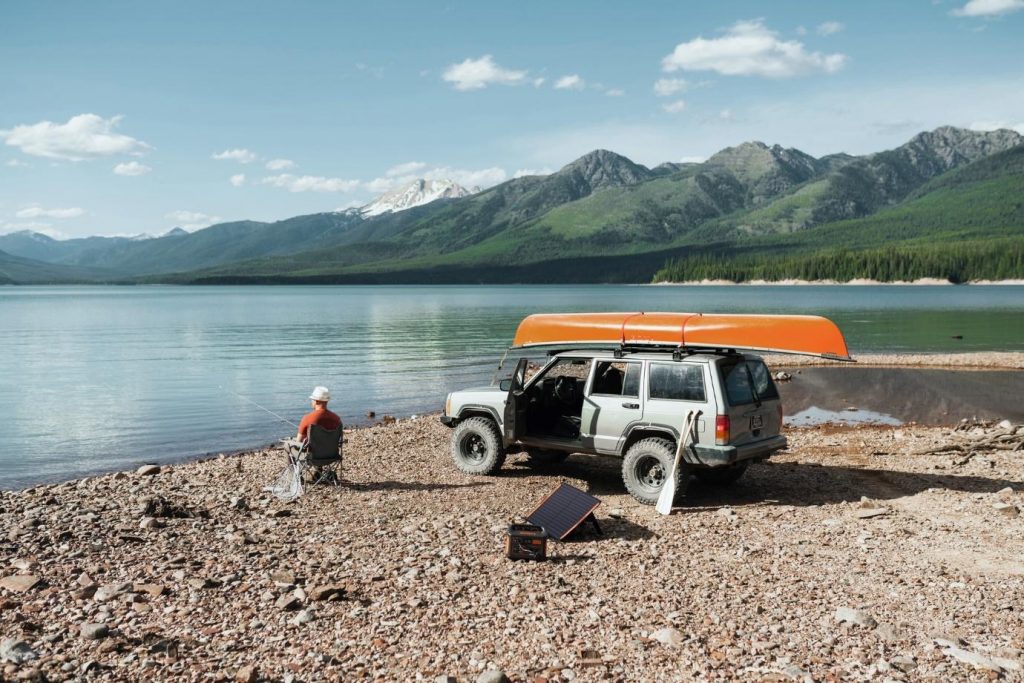 A portable generator on a beach beside an SVU with a canoe on top