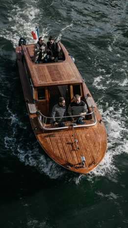 Four people aboard a wooden boat moving through water