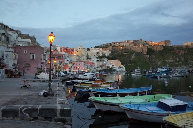 Botes de remos de colores amarrados en un puerto con edificios antiguos al fondo