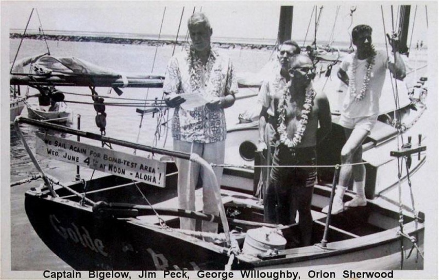 Old black-and-white photograph of four people on board Golden Rule boat with sign reading ‘We sail again for bomb-test area…’.