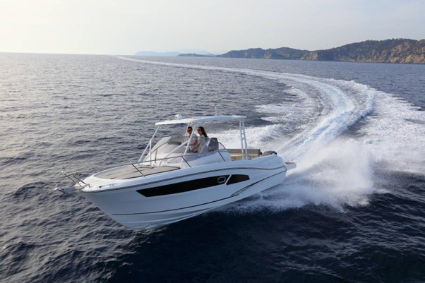 White powerboat seen from the front speeding across water in a curve.