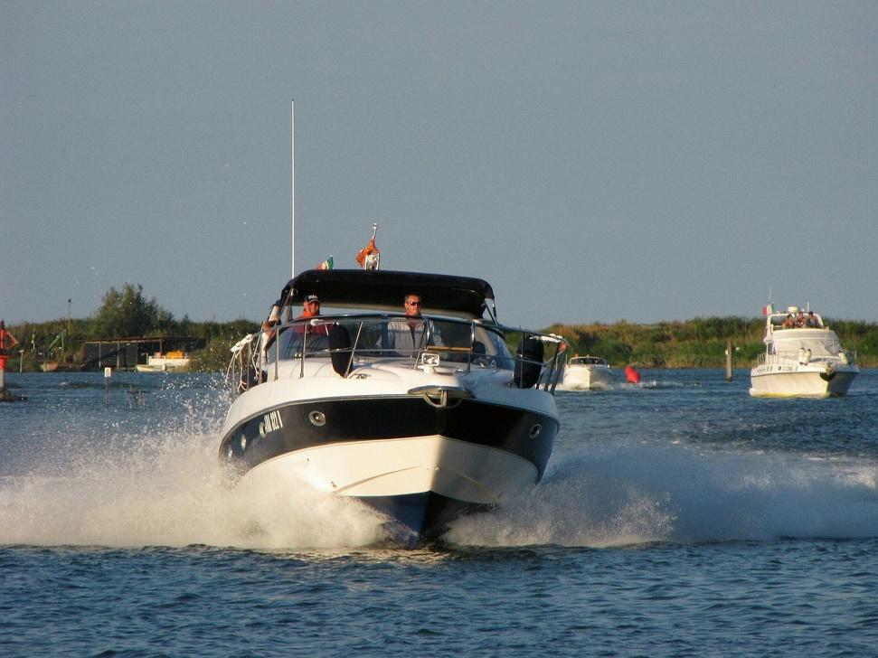 Two people aboard boat moving through water