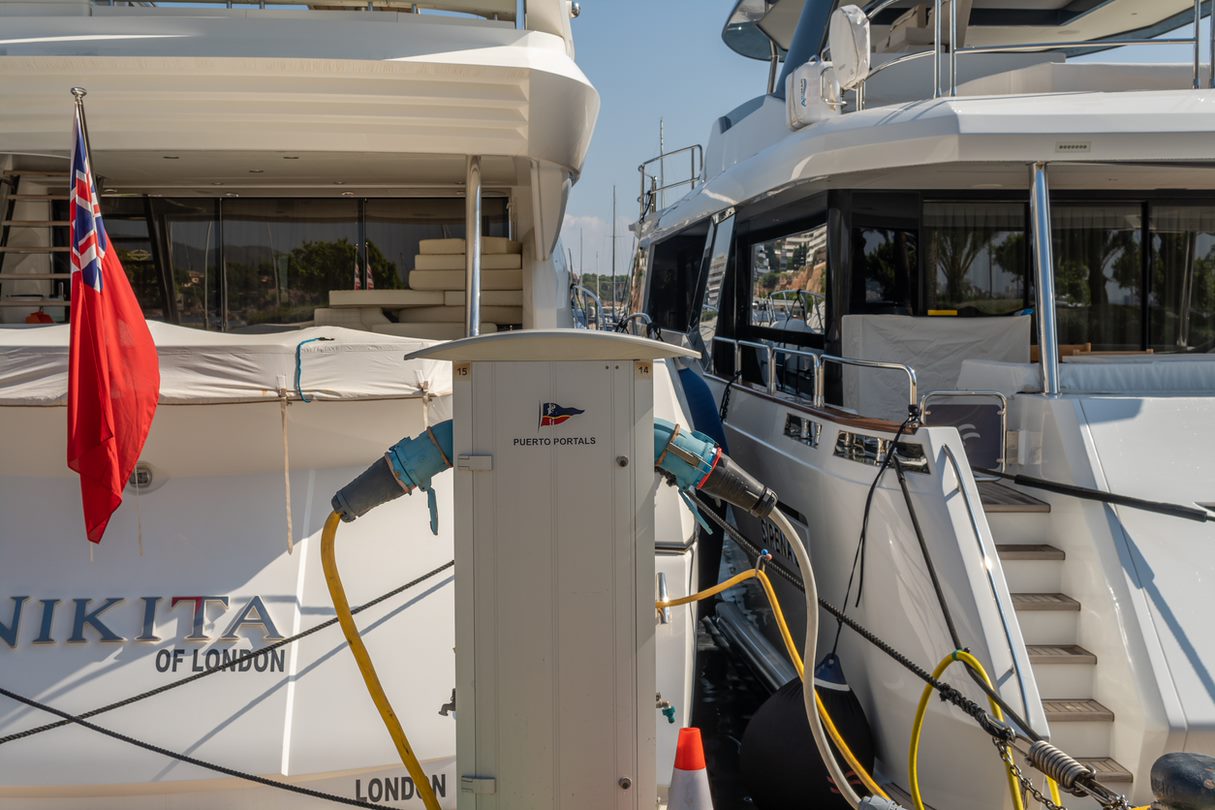 Close-up of a power outlet for boats, with two luxury yachts shown plugged in behind the outlet.