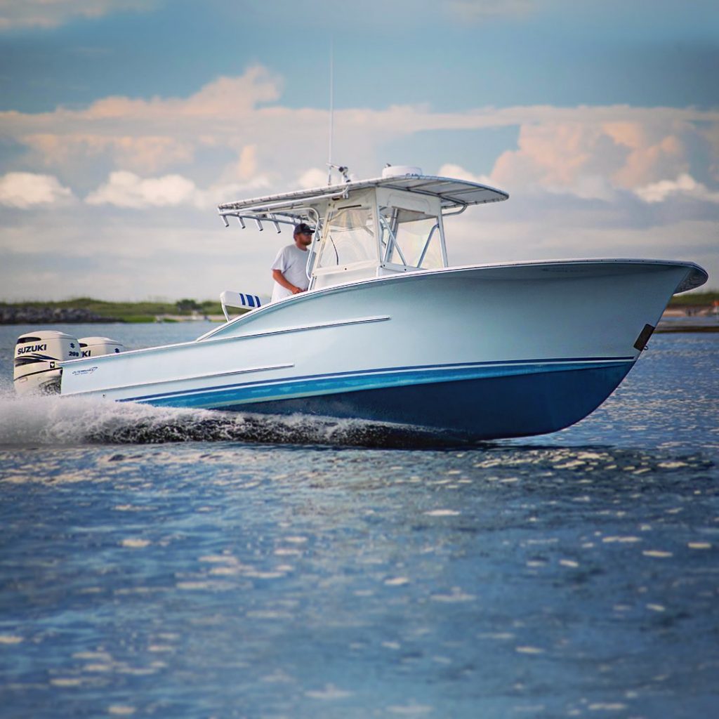 A side-facing view of a man driving a yacht through the water