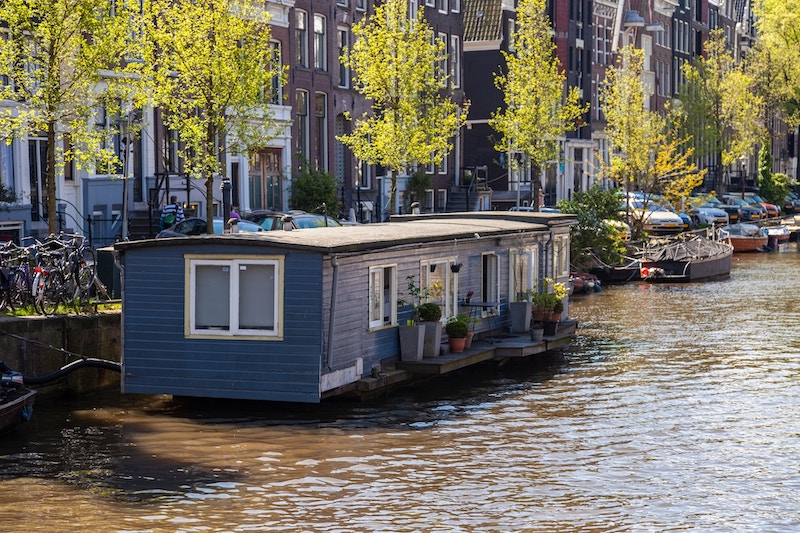 Een blauwgeverfde woonboot op een Amsterdamse gracht.