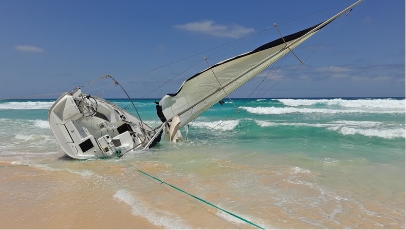 Een gestrande zeilboot gekanteld op het strand. 