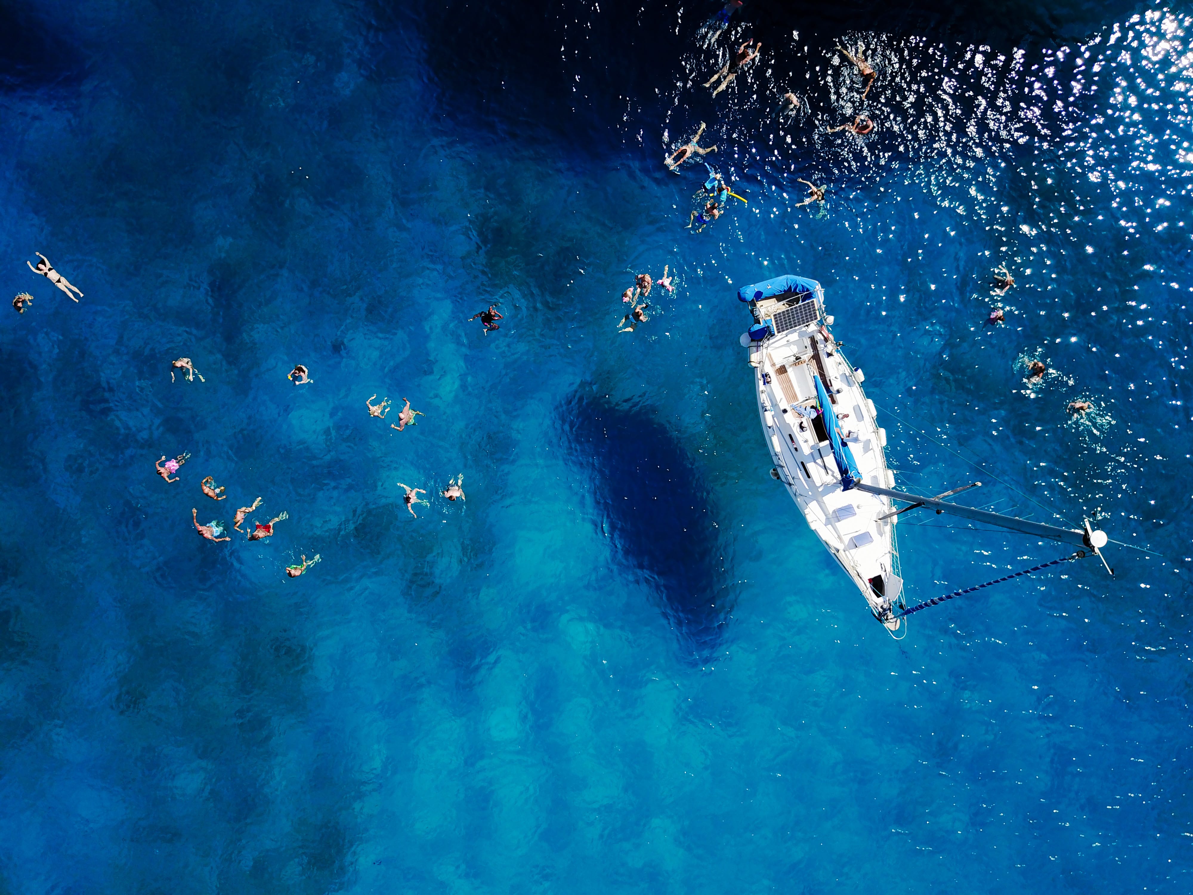 Aerial of sailing boat and people swimming