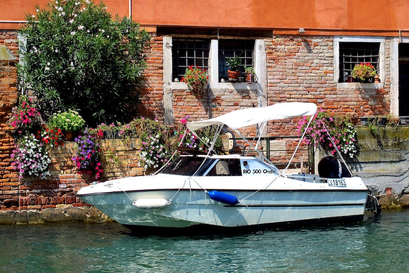 Boat moored in a river by a wall full of flowers