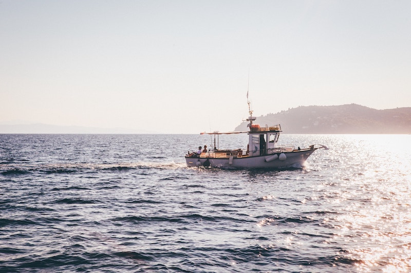 A small fishing boat out on the ocean in the evening sun.