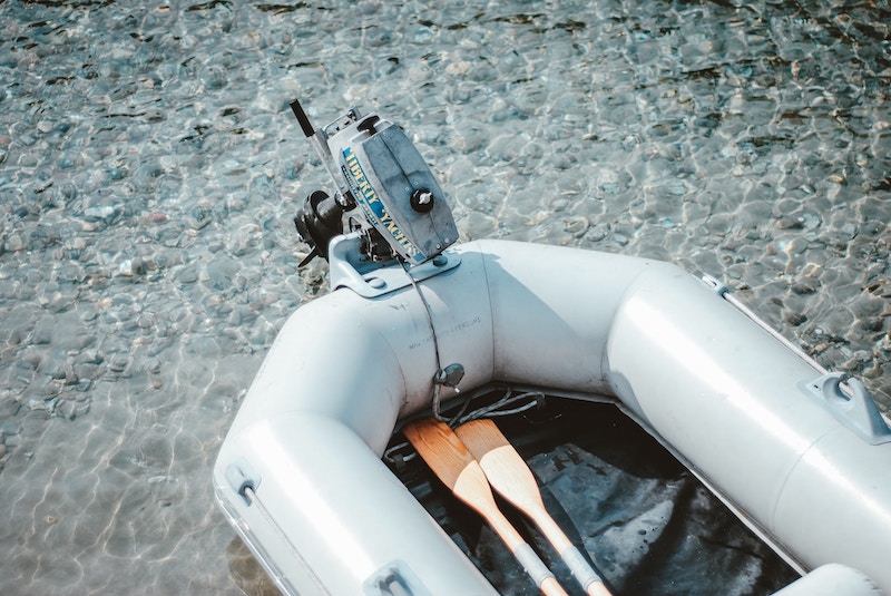 A light-coloured RIB with two wooden oars in shallow water.