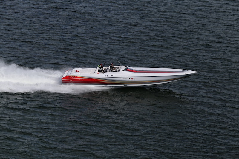 A red-and-white speedboat speeding through dark water.