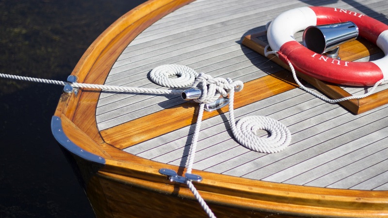 Mooi opgeruimd dek van een boot, met glanzende vernis en netjes opgerolde landvasten. 