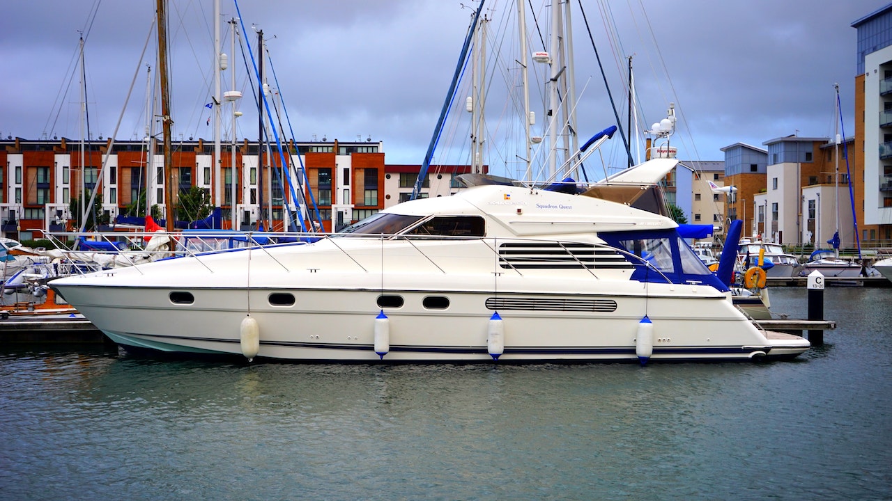 White power boat docked in marina, seen in profile from waterside.