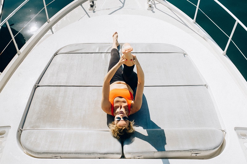 Vrouw doet yoga aan dek van een boot.