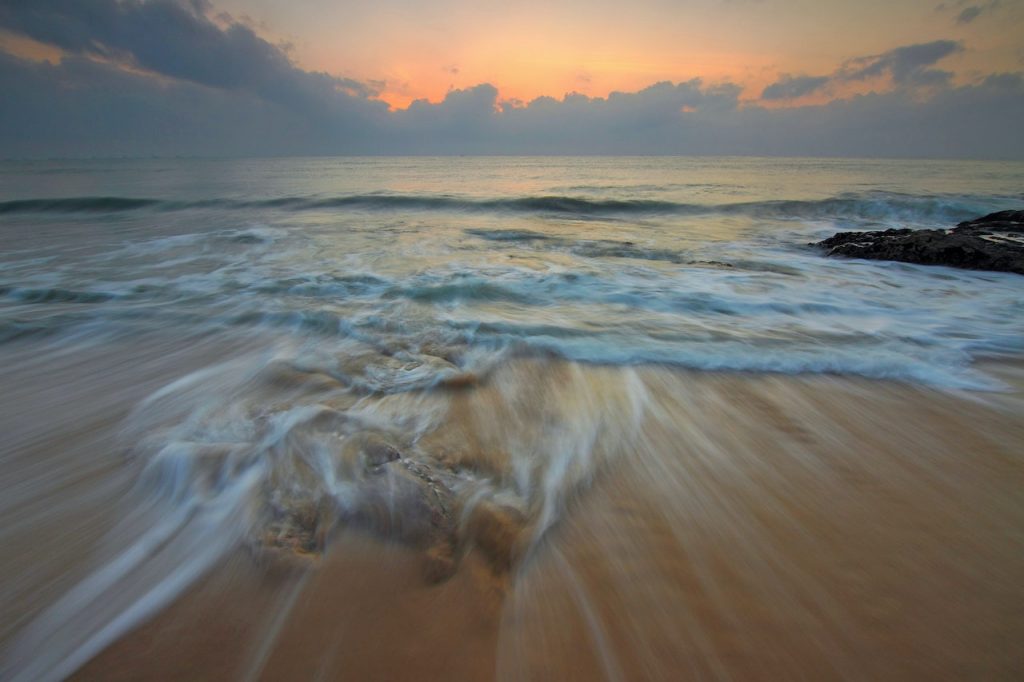  Image floue de l’eau se déplaçant rapidement au bord de l’océan au coucher ou lever du soleil