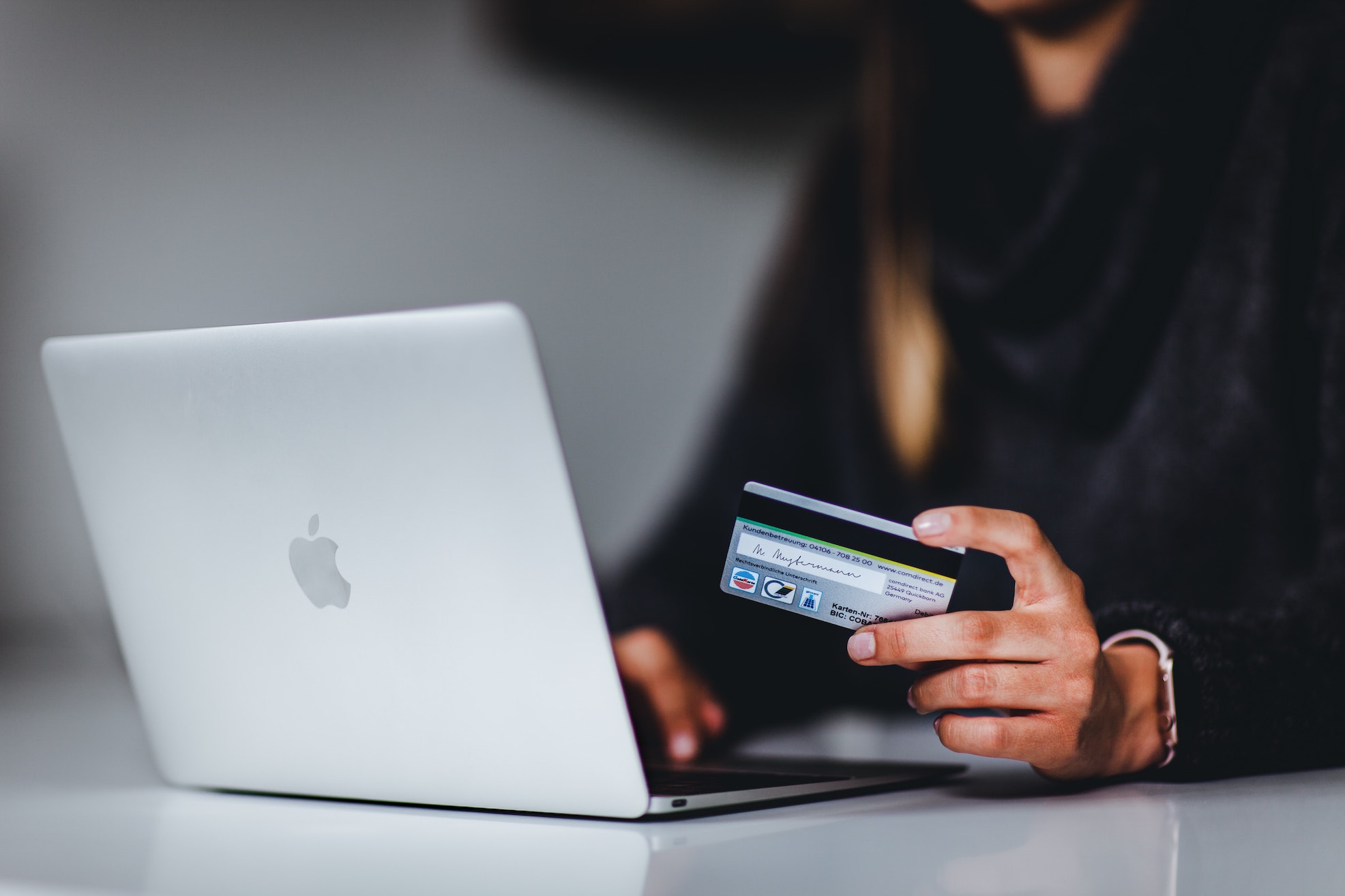 person using a laptop while holding a credit card 