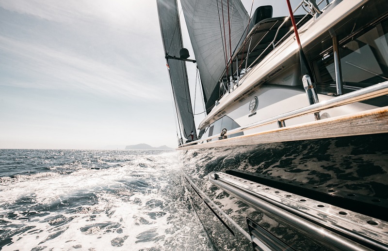 Close up taken from side of glossy-hulled luxury yacht, with wake in the background.