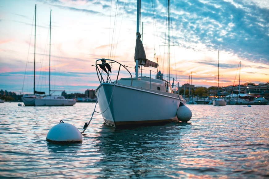 A small boat tied to a buoy among other boats in a harbour