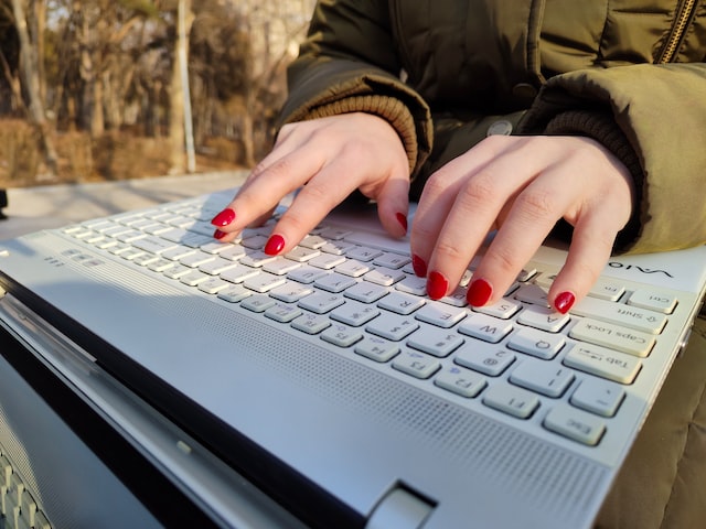 Frau tippt im Freien auf Laptop